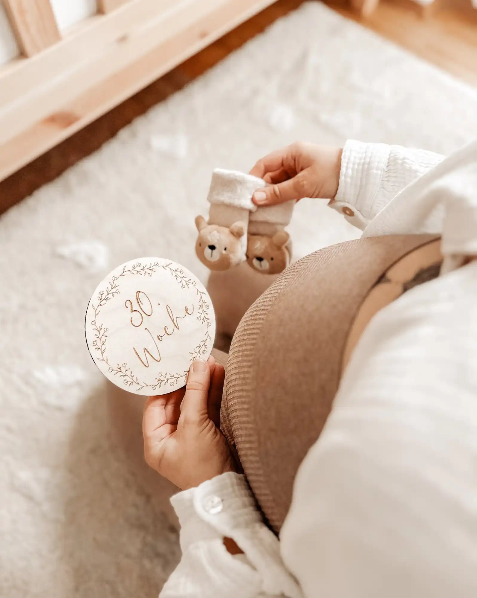 Ein schwanglicher Bauch mit einem Holzmeilenschild und Babyschühchen.